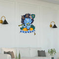 Wall decal of a blue-skinned figure playing a flute on a white wall above a sofa.